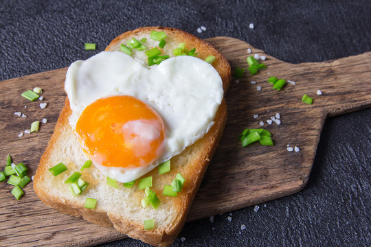 Fried egg on a toast with a green onion.