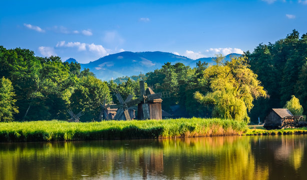 Dumbrava, Sibiu, Romania: Landscape of a lake with windmill in the golden light before sunset.