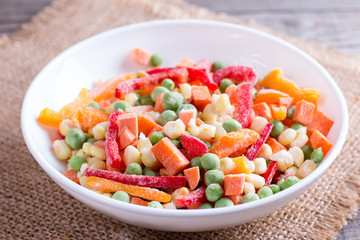 Mixed frozen vegetables in a plate on wooden table