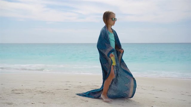 Little girl hve fun on the beach. Kid enjoy beach vacation with pareo