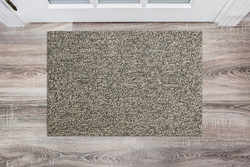 Blank beige woolen doormat before the white door in the hall. Mat on wooden floor, product Mockup