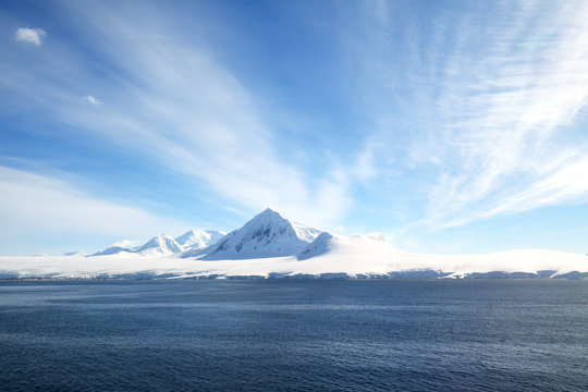 Antarctic ocean, Antarctica. Glacier Snow Covered Mountain. Dramatic blue Sky background