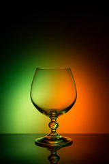 Wineglass on a color background with a black vignette. A tall Wineglass with a thin stalk
