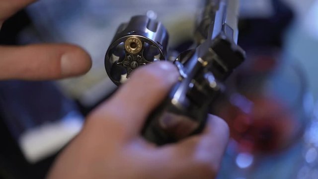 Man in desperate put bullet into revolver, playing Russian roulette, close up