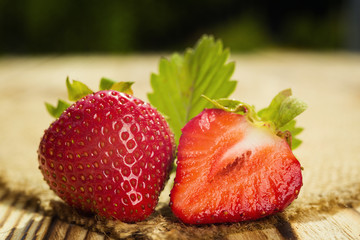strawberries on wooden table in natural background, delicious first class organic fruit as a concept of summer vitamins
