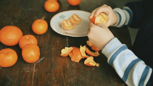 child cleans the tangerines on a wooden table
