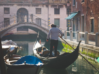 Fototapeta na wymiar Couple of tourists enjoying gondola tour in the water channel of Venice