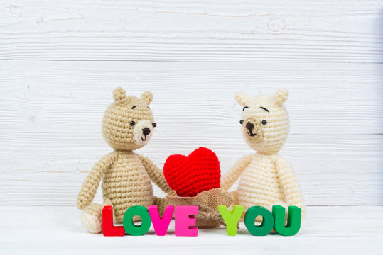 Sweet couple teddy bear doll in love with Love text and red knitting heart on white wooden background and copy space for add text and picture, love and valentine day concept.