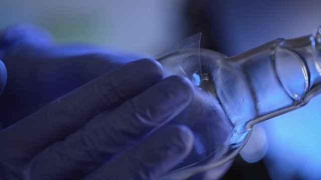 Fingerprints lifting from glass bottle, forensic examination, hands close up