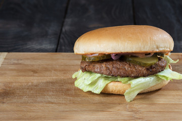burger/ Classic burger on a wooden board with pickled cucumbers and onions with a large fried chop