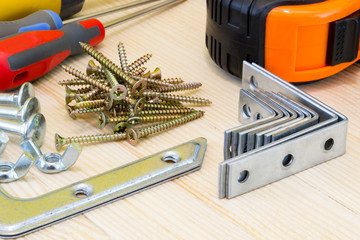 Woodwork tools and screws at the wood planks on yellow background