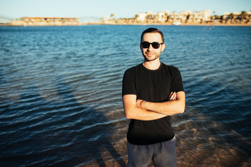 Fototapeta premium Young handsome man wearing spectacles and having fun on sea beach