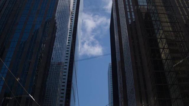looking up and slowly tracking ahead we see a tunnell of sky scrapers. sunny blue sky.