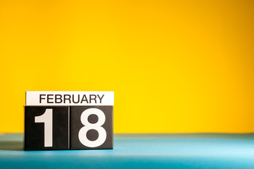 February 18th. Day 18 of february month, calendar on yellow background. Winter time. Empty space for text
