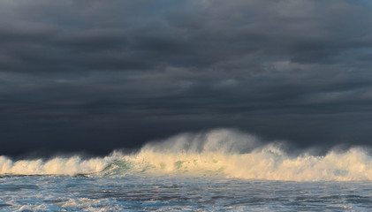 Splashing wave against a stormy sky. Powerful ocean wave breaking. Wave on the surface of the ocean. Wave breaks on a shallow bank.