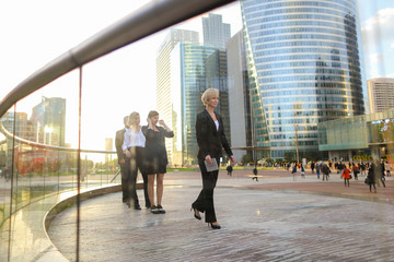 Satisfied businesswoman walking with document case and partners 