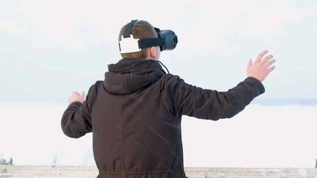 young man getting experience in using VR-headset outdoor at winter park,
