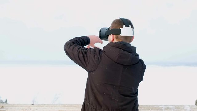 young man getting experience in using VR-headset outdoor at winter park,