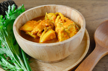 Thai food Curry yellow soup of fish and baby coconut meat serve in wooden bowl and vegetable.