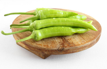 Indian organic long green chiles, banana pepper, or Ooty chile, which are mildly spicy or hot on a wooden table.