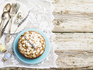Simple homemade pecan pie decorated with petals of almond with a wooden background Serving Easter used blue and yellow colors, quail eggs, lavender flowers, vintage linen tablecloth handmade.