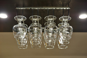 a row of wine glasses hang upside down in the bar