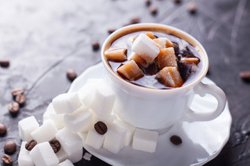 Sugar addict. Heap overabundance of sugar in a cup of coffee on a black table with scattered coffee beans