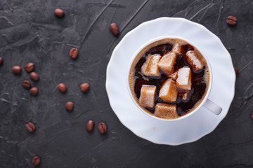 Sugar addict. Heap overabundance of sugar in a cup of coffee on a black table with scattered coffee beans. Top view