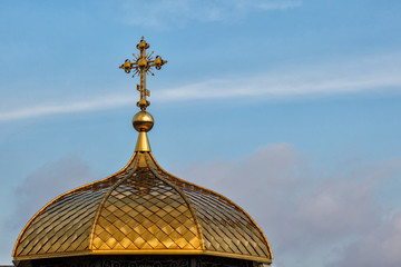 Fototapeta na wymiar Gilded dome of orthodox Christian church shines on the blue sky background