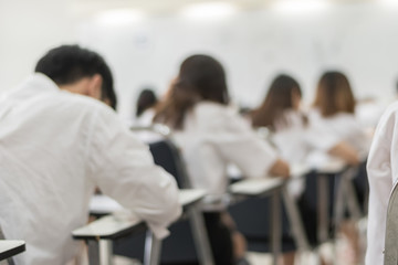 Fototapeta na wymiar Blur school background university students writing answer doing exam in classroom .
