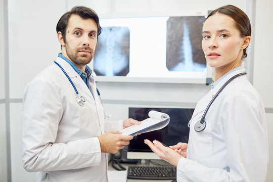 Two young radiologists in uniform looking at camera during work