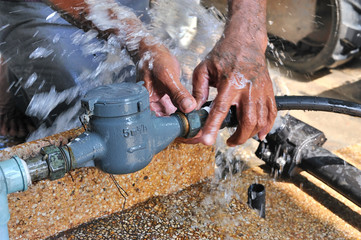 Close-up of worker hands plumbing unscrew connecting pipe while water leak.