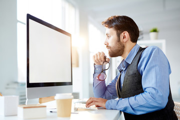 Fototapeta premium Modern manager or designer concentrating on reading online information on monitor display