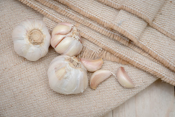 Organic garlic bulbs on burlap background.