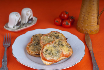 Hot sandwitch with tomatoes and cheese on a plate on a red dressed table.