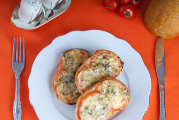 Hot sandwitch with tomatoes and cheese on a plate on a red dressed table.