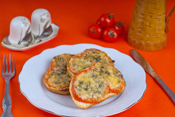 Hot sandwitch with tomatoes and cheese on a plate on a red dressed table.