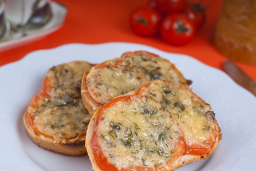 Hot sandwitch with tomatoes and cheese on a plate on a red dressed table.