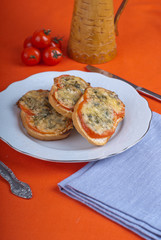 Hot sandwitch with tomatoes and cheese on a plate on a red dressed table.