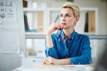 Serious mature teacher with eyeglasses thinking of working questions at workplace