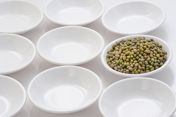 raw mung bean in small bowls  by circle shape repetition in white background.