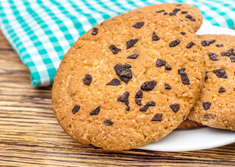 Cookies with chocolate on plate with kitchen towel on the table.