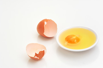 Broken eggshells with egg yolks in white bowl