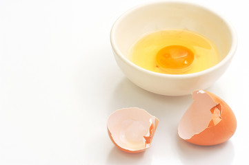 Broken eggshells and egg yolks in bowl with space white background.