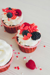 Cupcakes with white cream, fresh berries and decoration