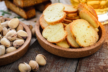 Snacks to beer, crackers, pistachios and a glass of light beer on a wooden table.