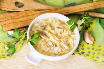 noodle soup with chicken and parsley on tablecloth and wooden table
