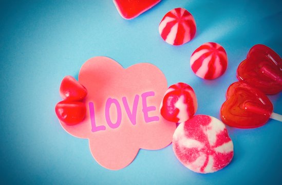 congratulatory card with gummy candies and heart shaped lollipops on blue background