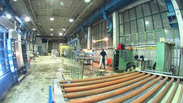 Workers applying robotic machine for cutting glass, conveyor processing, glass manufacturing