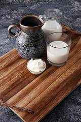 milk products - tasty healthy dairy products on a table sour cream in a bowl, cream and milk jar